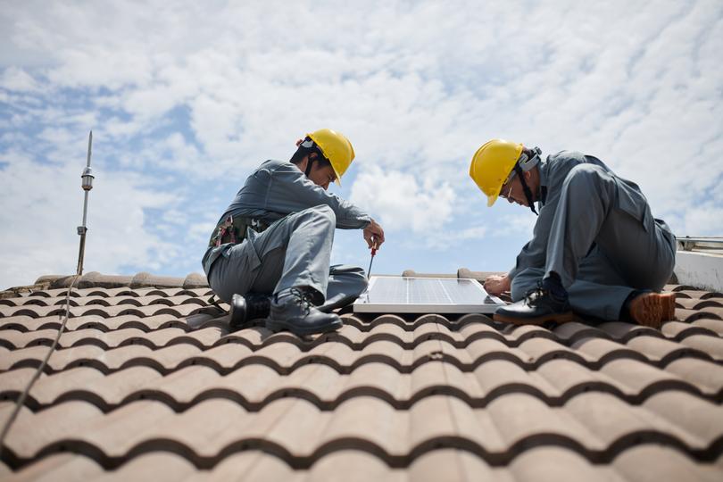 Technician inspecting solar panels on a residential roof in USA