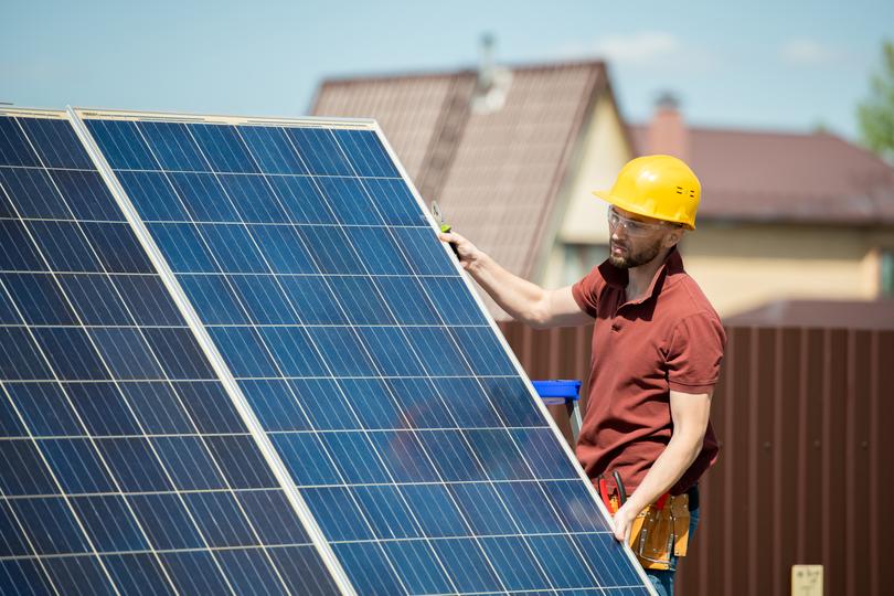 Technician inspecting solar panels on a residential roof in USA