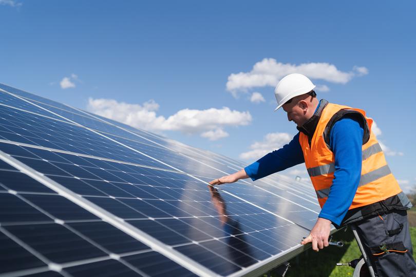 Technician inspecting solar panels on a residential roof in USA