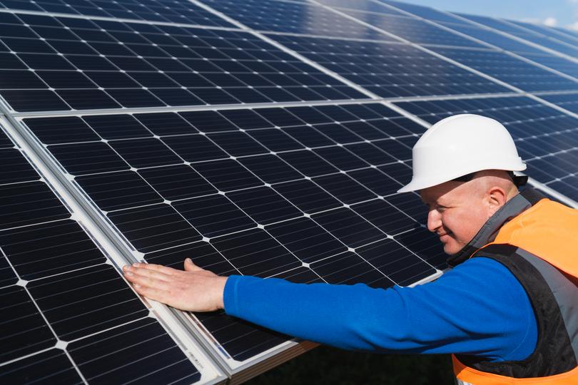 Technician inspecting solar panels on a residential roof in USA