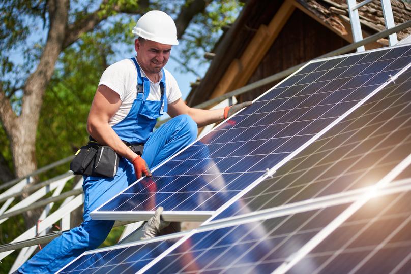 Technician inspecting solar panels on a residential roof in USA